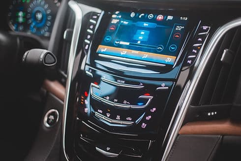 A vehicle dashboard and centre console with the controls lit up.